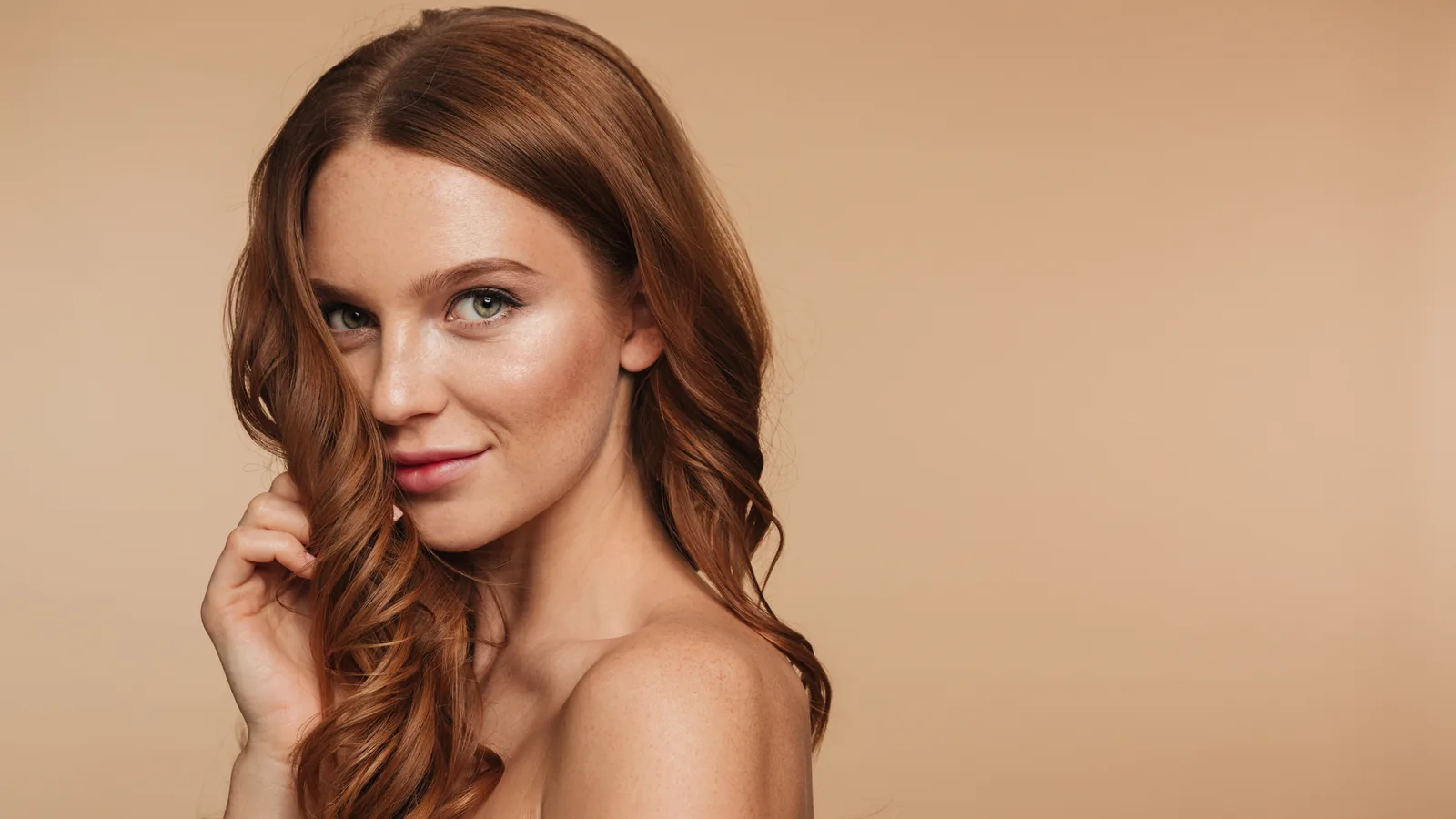 Portrait of a woman with long red hair against a beige background