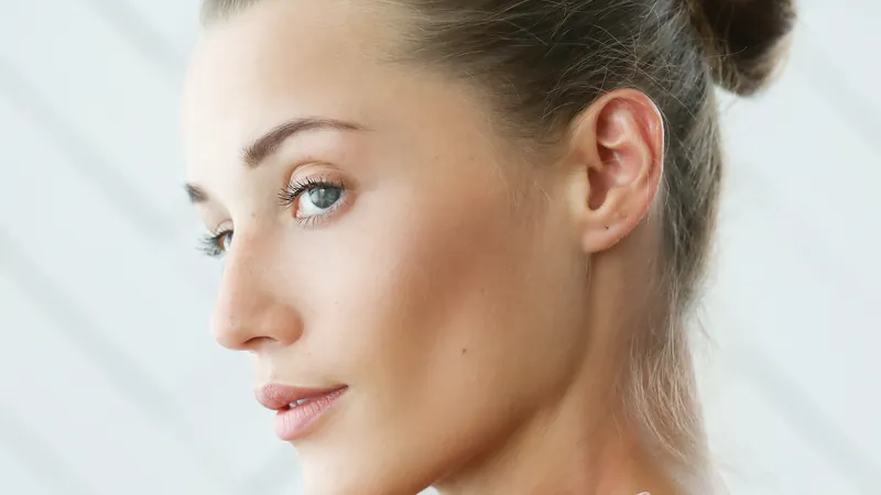 Woman seen from behind over a bare shoulder, looking towards the camera