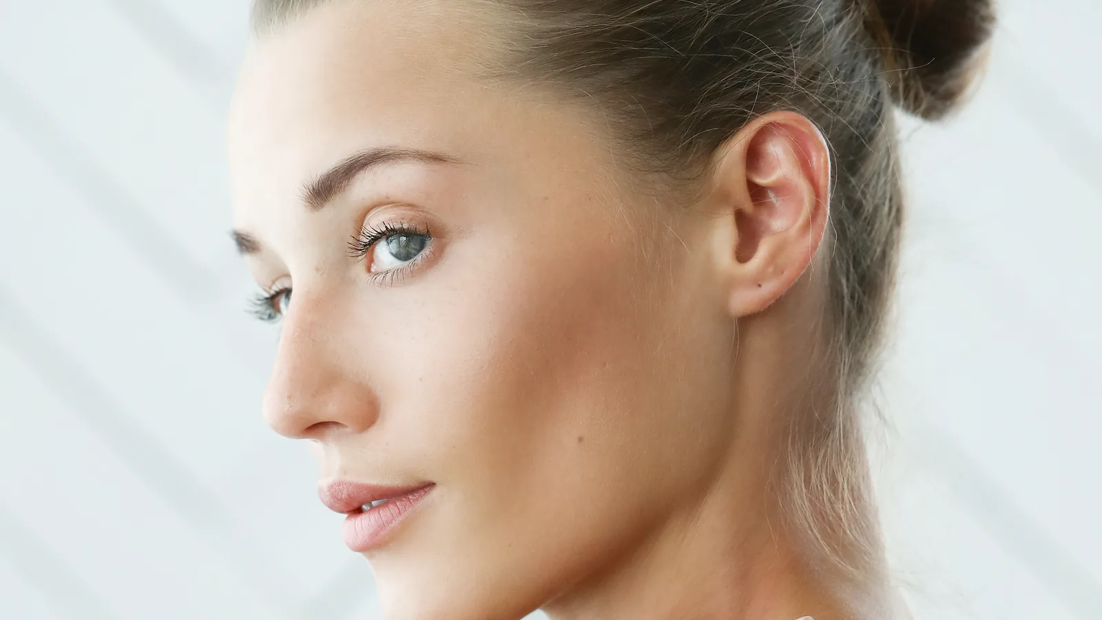 Woman seen from behind over a bare shoulder, looking towards the camera