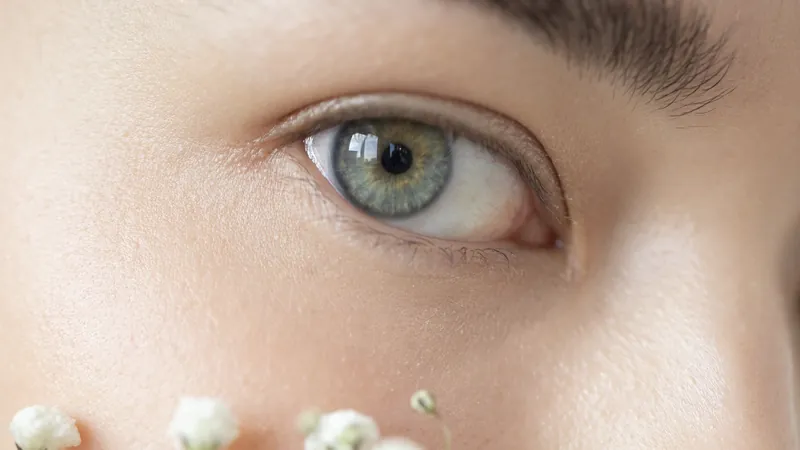 Close-up of an eye with small white flowers resting on the cheek below it