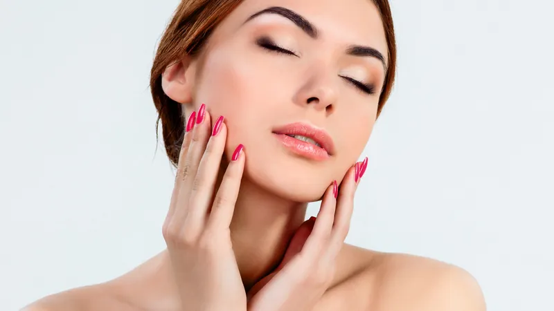 Woman framing her face with both hands, wearing natural makeup