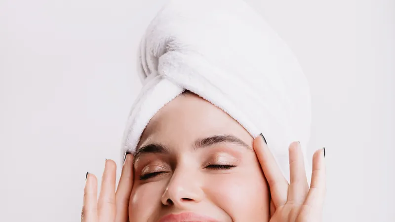 Woman in a towel turban laughing in front of a round bathroom light