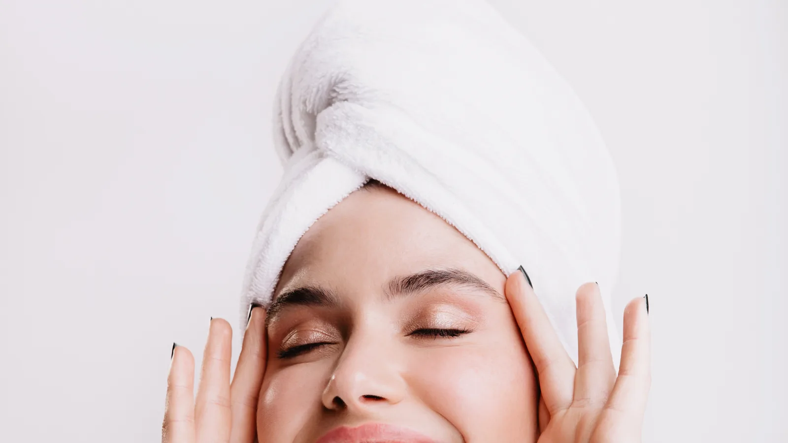 Woman in a towel turban laughing in front of a round bathroom light