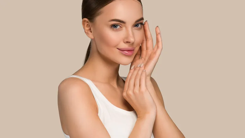 Woman in a white top touching her cheek, beige background