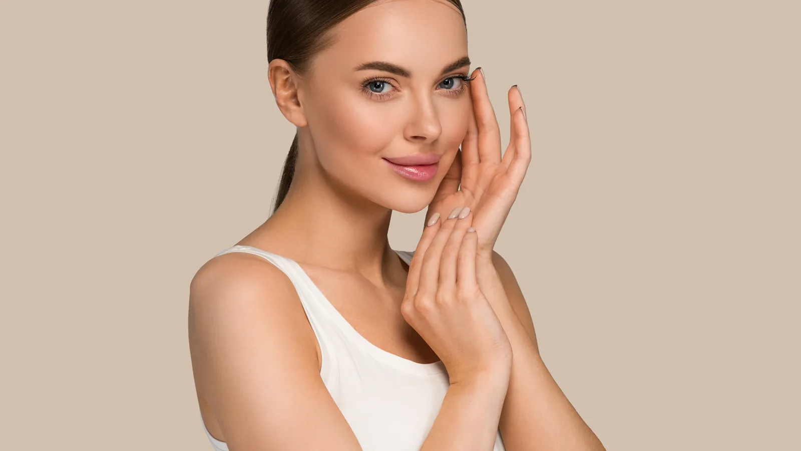 Woman in a white top touching her cheek, beige background